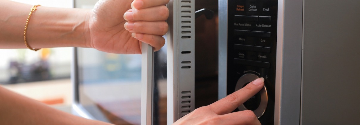 Woman's Hands Closing Microwave Oven Door And Preparing Food in microwave.