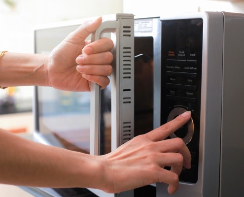 Woman's Hands Closing Microwave Oven Door And Preparing Food in microwave.