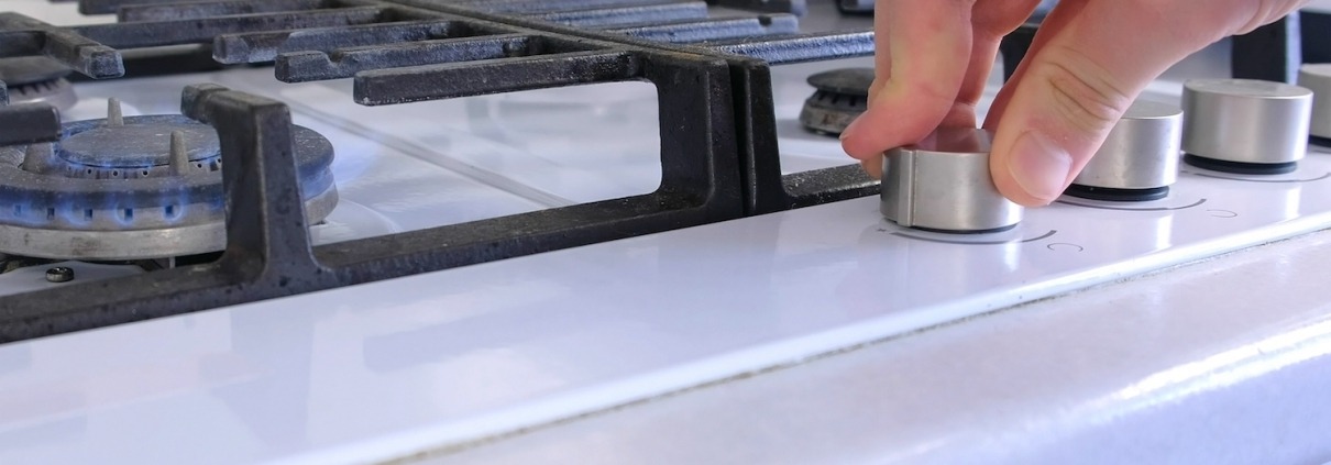 a hand turns on the knob for a gas stovetop oven range