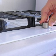 a hand turns on the knob for a gas stovetop oven range