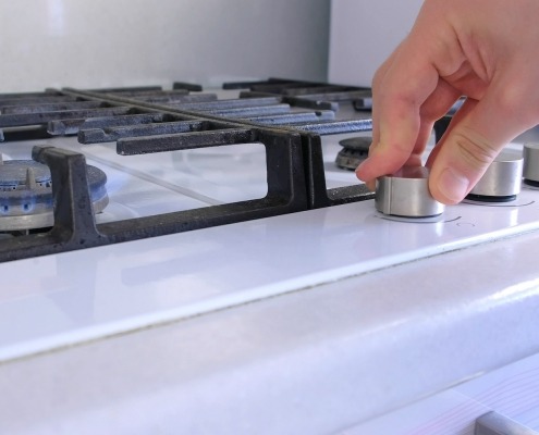 a hand turns on the knob for a gas stovetop oven range