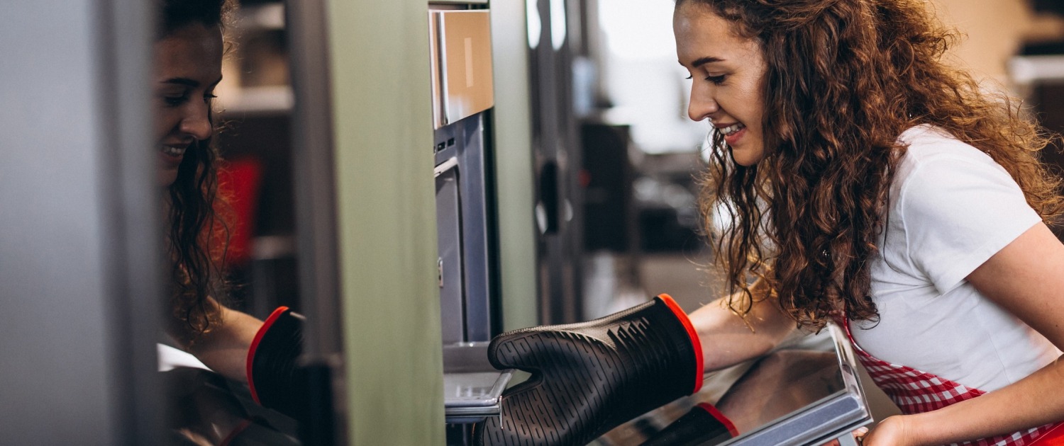 Woman taking food out of the oven; how to calibrate your oven article