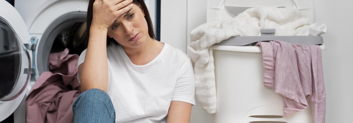 Woman looking frustrated sitting in front of the washing machine
