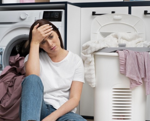 Woman looking frustrated sitting in front of the washing machine