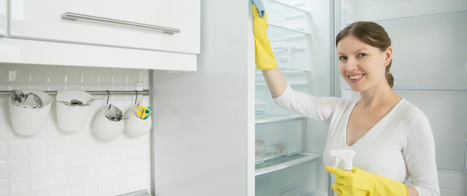 Young smiling woman wearing rubber gloves cleaning the fridge, photo by Yanalya on Freepik.com