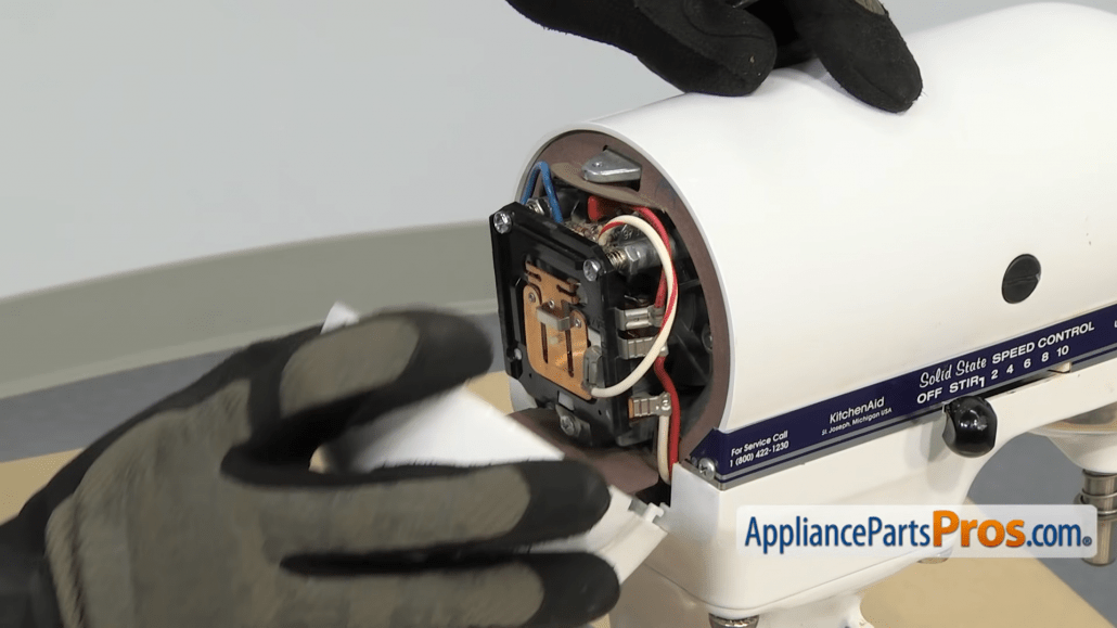 Gloved hands removing the back cover on the head of the Kitchenaid stand mixer