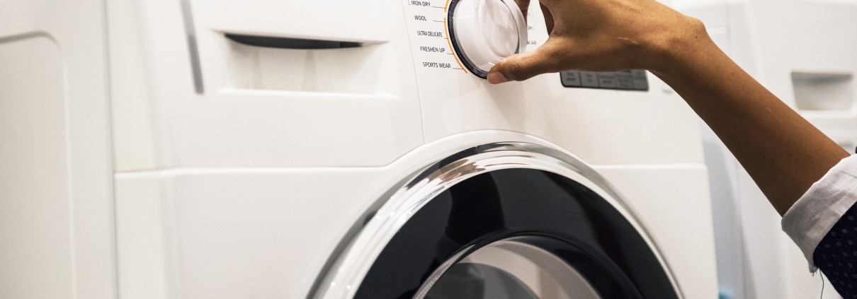 Woman's hand on the dial of a All-In-One Washer Dryer