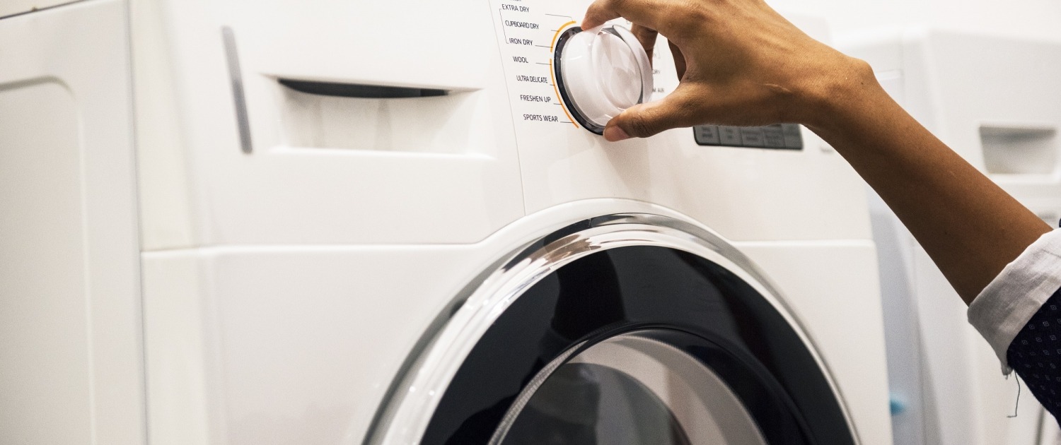 Woman's hand on the dial of a All-In-One Washer Dryer