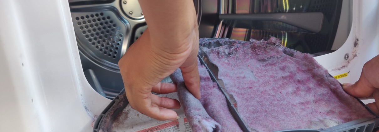 Hand removing lint from the lint filter of a dryer