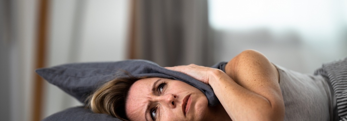 Lady lying down covering her head with a pillow