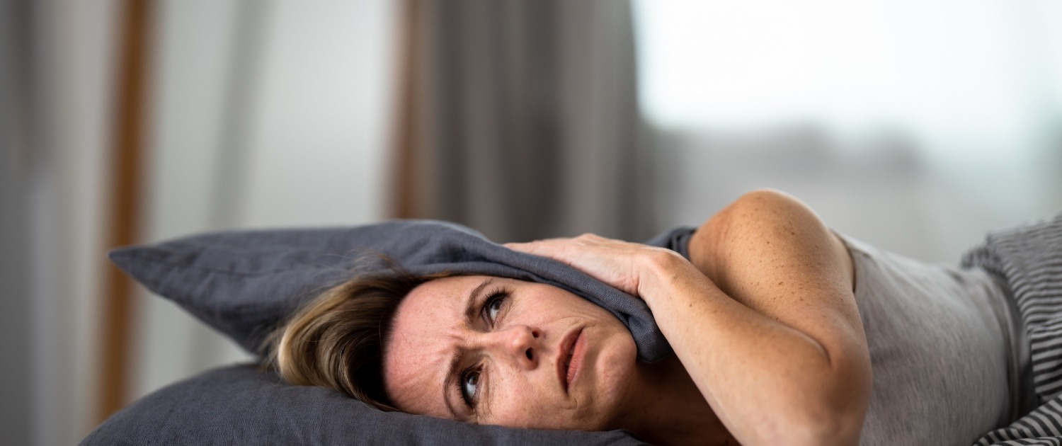 Lady lying down covering her head with a pillow