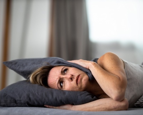 Lady lying down covering her head with a pillow