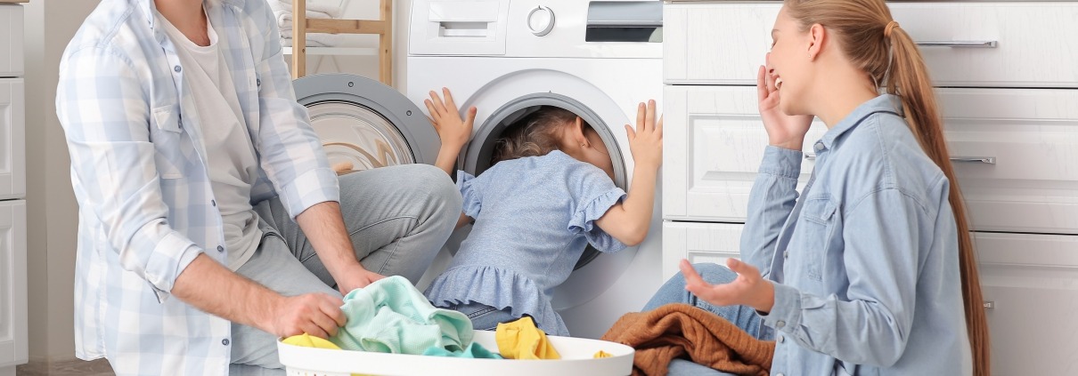 A mother, father, and child do laungry together in front of high efficiency washing machine
