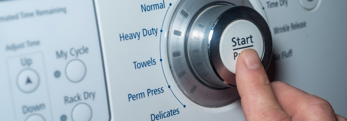 Finger pushing start button to choose dryer setting
