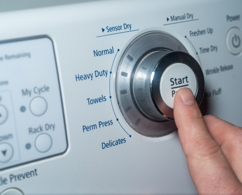 Finger pushing start button to choose dryer setting