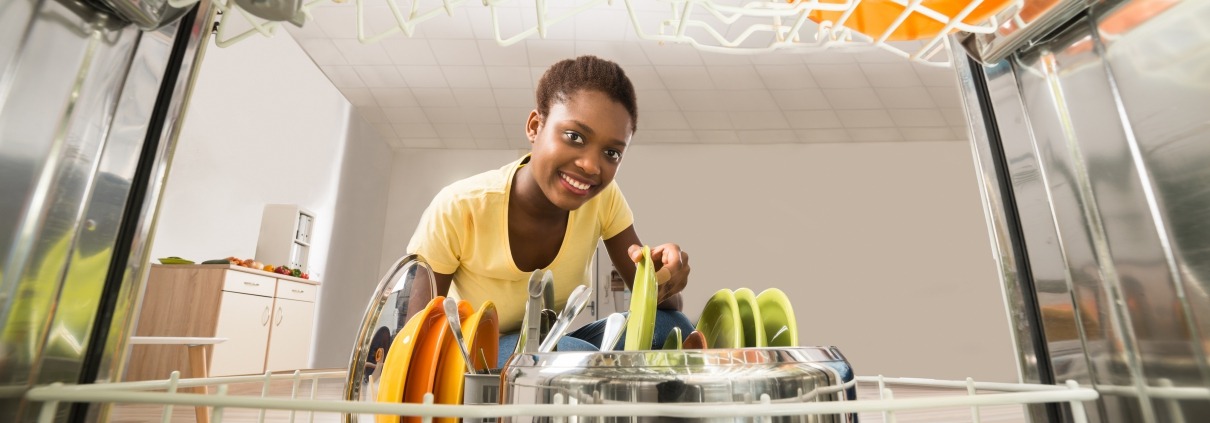 Young African American woman takes a plate out of a Whirlpool dishwasher