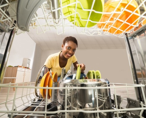 Young African American woman takes a plate out of a Whirlpool dishwasher