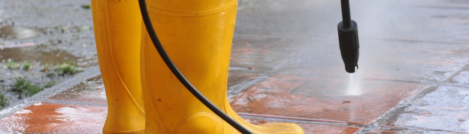person wearing yellow rubber boots with high-pressure water nozzle cleaning the dirt in the tiles. Image by wirestock on freepik.com
