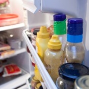 condiment bottles on a refrigerator shelf behind the fridge door shelf bar