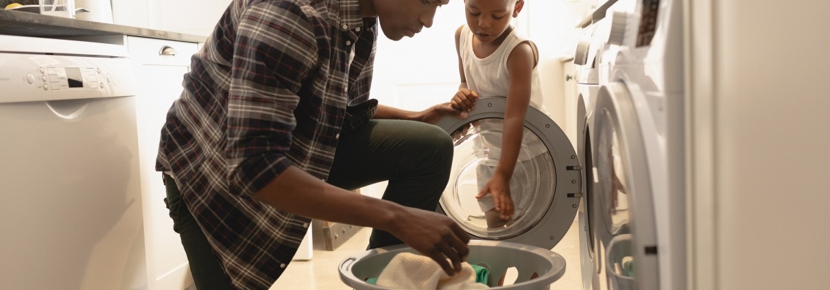 African American father and son do laundry in front of the dryer