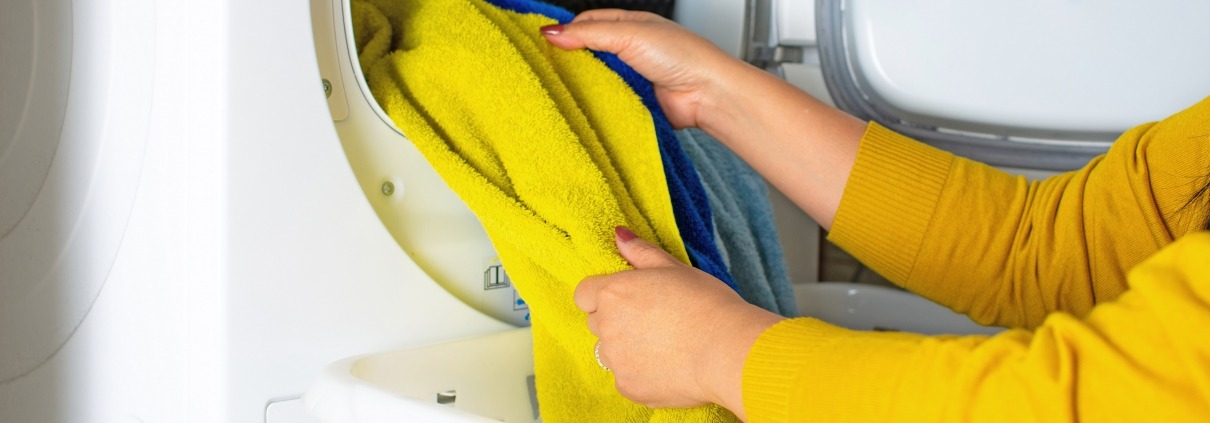 Cropped view of young woman taking clothes out of the dryer