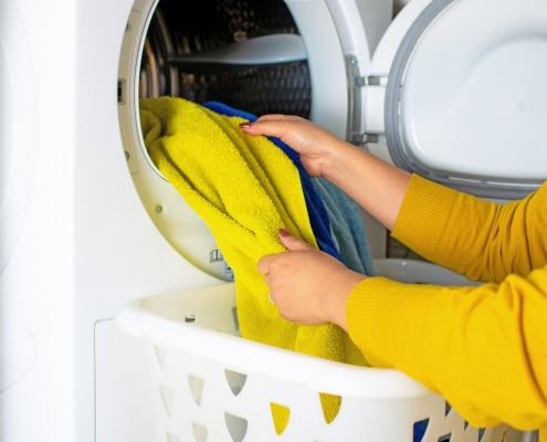 Cropped view of young woman taking clothes out of the dryer