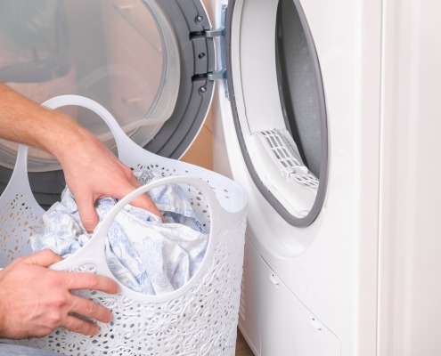 hands grabbing laundry in front of a dryer
