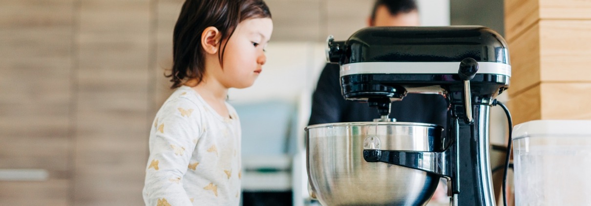 Toddler girl peeking into Kitchenaid stand mixer
