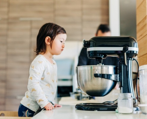 Toddler girl peeking into Kitchenaid stand mixer