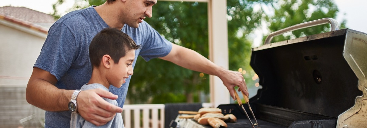 father teaching son how to grill