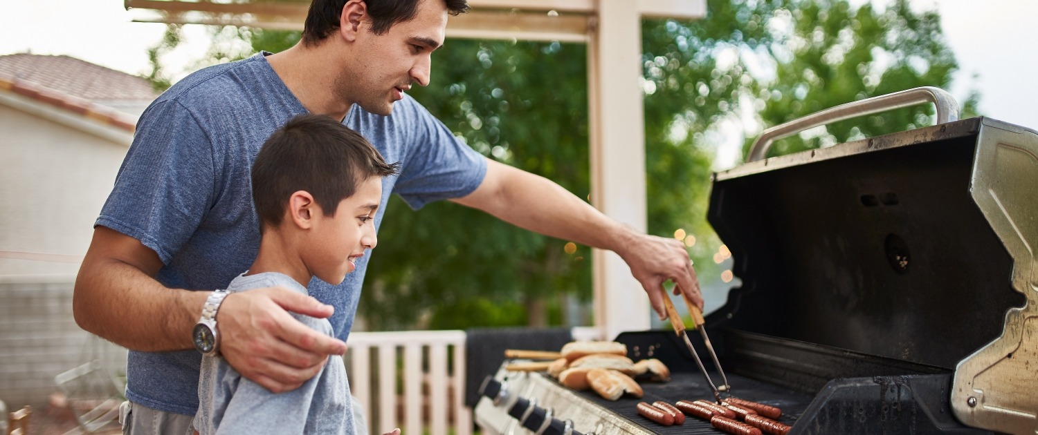 father teaching son how to grill