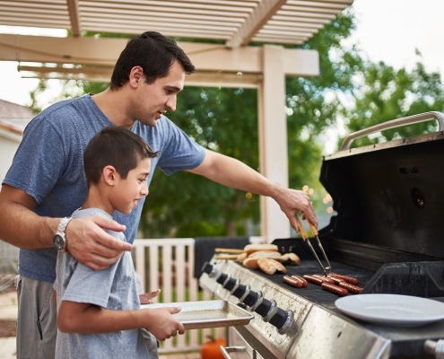 father teaching son how to grill