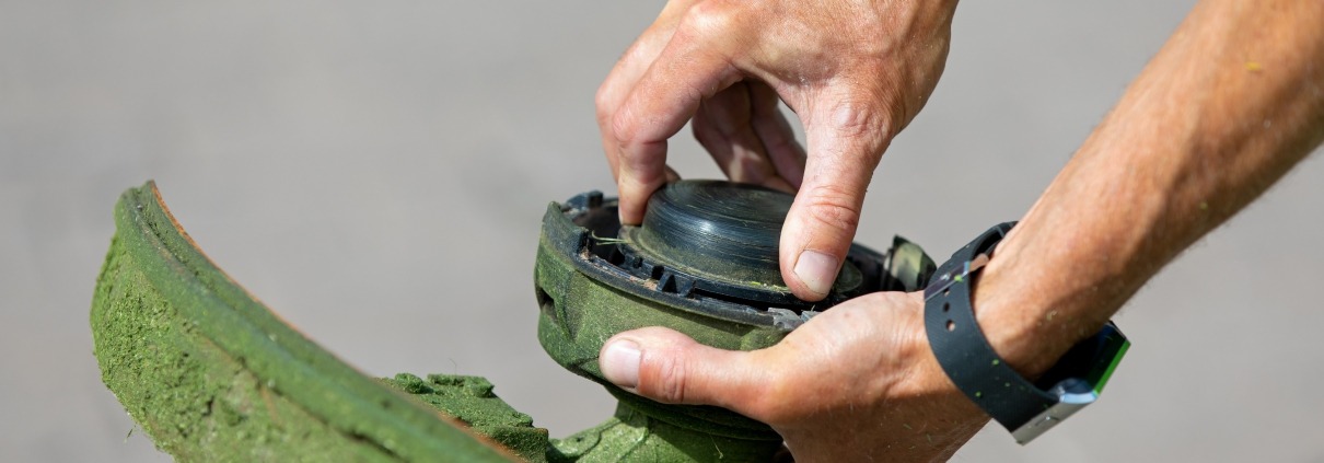 Close up of hands doing maintenance on a weed eater