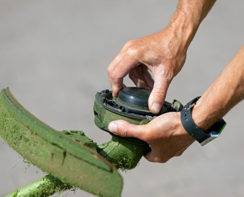 Close up of hands doing maintenance on a weed eater