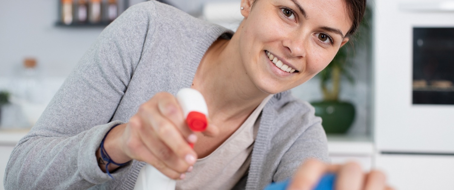 Woman smiling while cleaning the kitchen