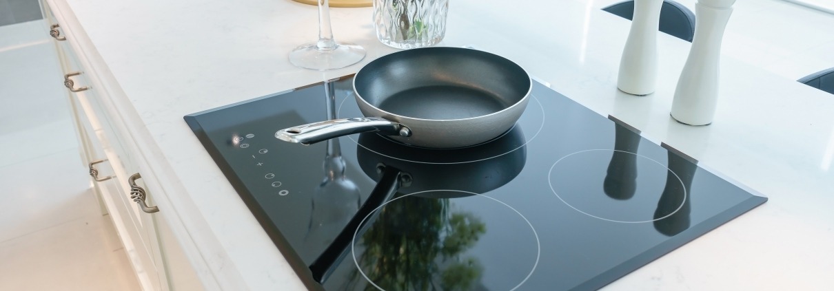 Frying pan induction cooktop stove in white kitchen interior