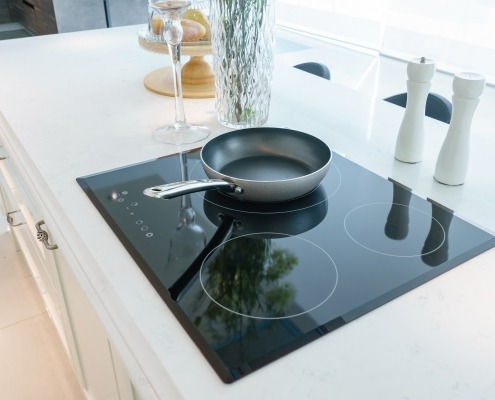 Frying pan induction cooktop stove in white kitchen interior
