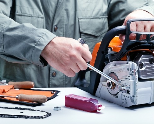 Man repairing chainsaw and doing tool maintenance