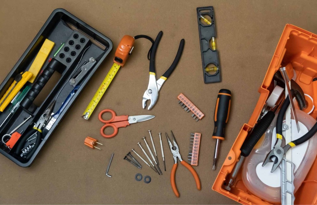 Assorted tools required for electric oven installation, including screwdrivers, pliers, wire strippers, electrical tape, level, and drill