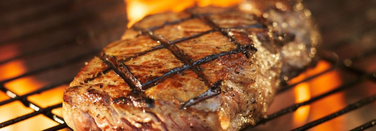 meat cooking on grill with flames