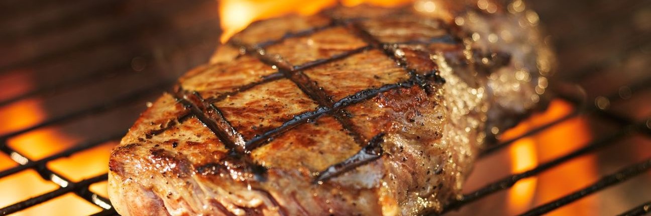 meat cooking on grill with flames