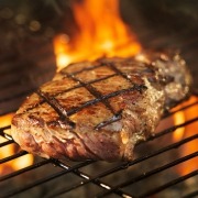 meat cooking on grill with flames