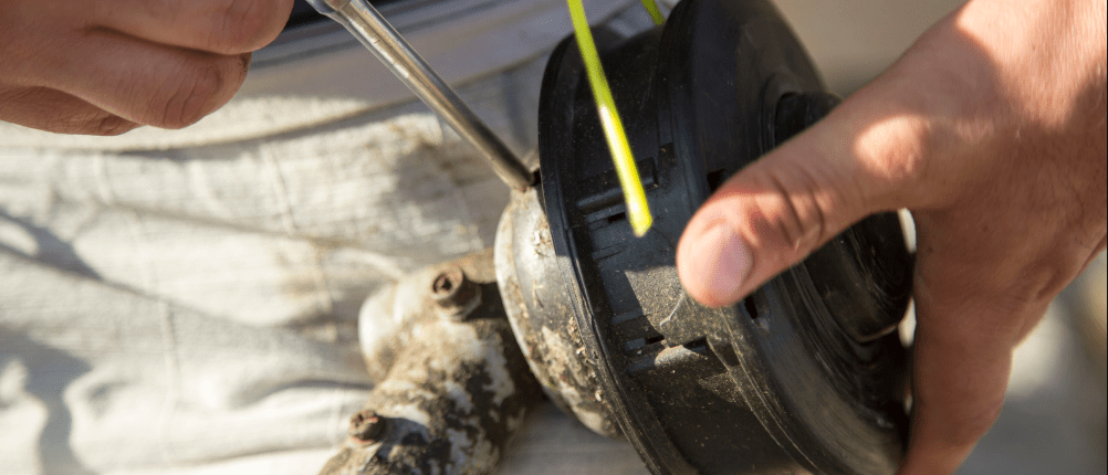 Close up of hands demonstrating how to restring your weed eater