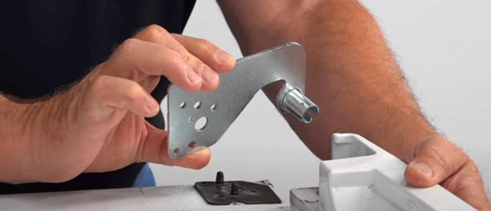 close up of hands replaceing the upper door hinge on a refrigerator
