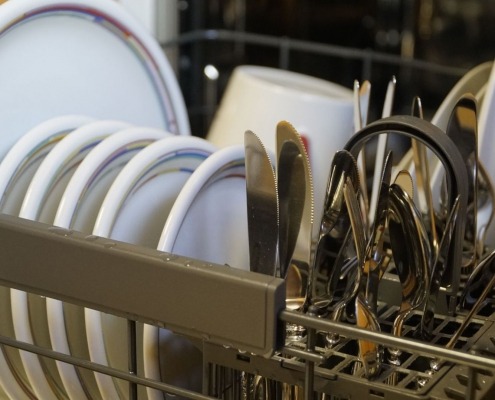 open dishwasher door with a rack full of dishes in kitchen