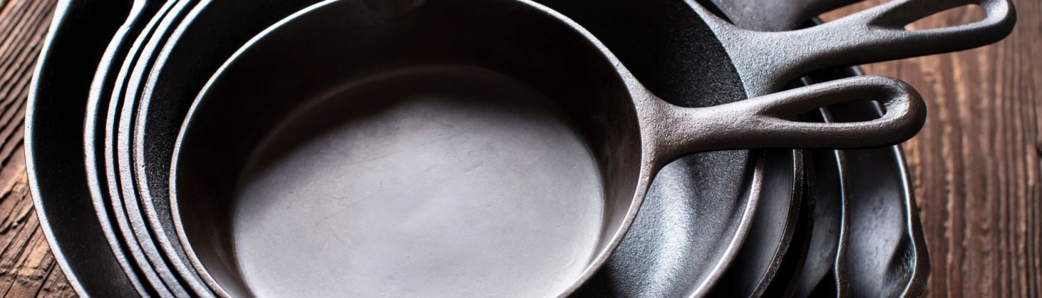 season cast iron skillets stacked together on wooden table
