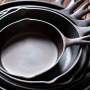 season cast iron skillets stacked together on wooden table