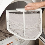 open dryer door with man holding full lint trap