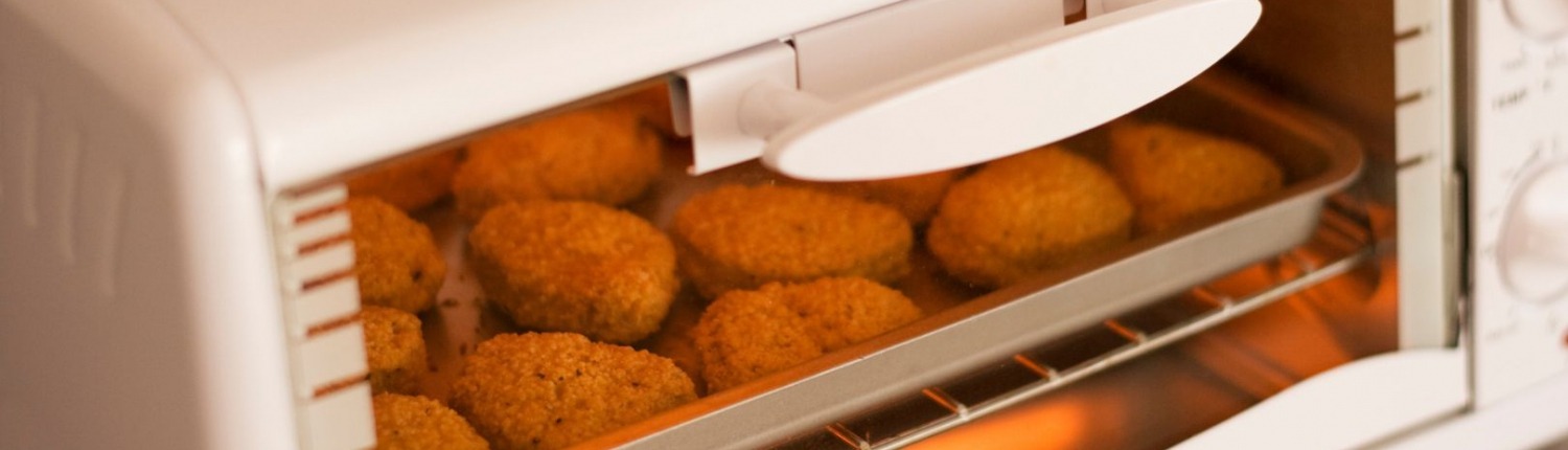 closed toaster oven with breaded meat cooking inside