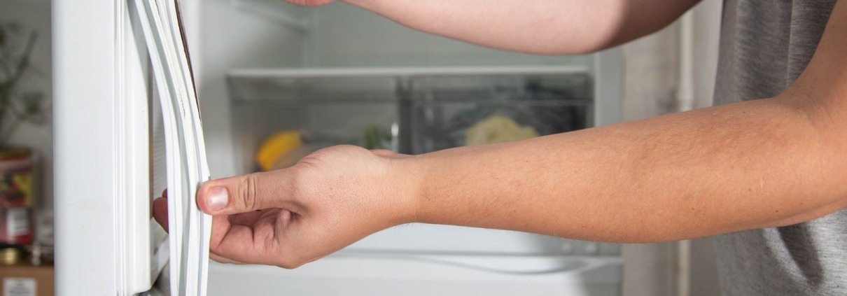 person's hands applying new seal to refrigerator door